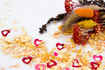 Fototapeta na wymiar Valentine's day background. Dried flowers, gold powder and hearts. Red, gold and white