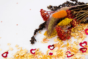 Valentine's day background. Dried flowers, gold powder and hearts. Red, gold and white