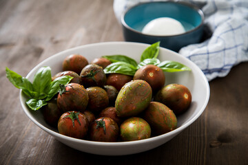 Gestreifte bunte Tiger Tomaten in Schale mit Mozzarella und Basilikum mit Geschirrtuch auf Holz 