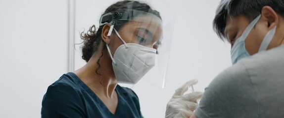 CU Portrait of African American female doctor administering vaccine to a Chinese patient in vaccination cabin. COVID-19 coronavirus vaccination - Powered by Adobe