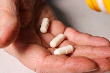 An elderly woman pours pills from a jar into her hand. Elderly health concept. Nursing and caring for elderly parents. Selective focus.