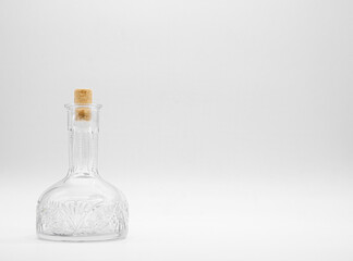 Empty glass carafe closed with cork cap isolated on a white background. Transparent bottle. Front view of the vertical staying jar.