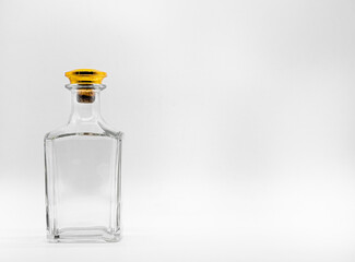 Empty glass bottle closed with big golden round cork isolated on a white background. Transparent square bottle. Front view of the vertical staying jar.
