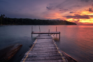 Fototapeta premium The long-exposure scenery of a beautiful twilight sky in sunset time over the wooden pier in Koh Kood island, Trat, Thailand.