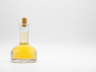Glass carafe with alcohol drink closed with cork cap isolated on a white background. Transparent bottle with yellow liquid. Front view of the vertical staying jar.