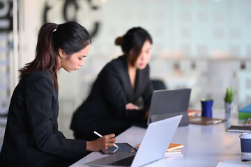 Two businesswoman working and planning a strategy in modern office.