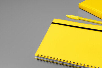 Yellow notepad with yellow pencil on gray background