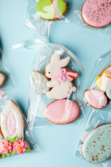 Easter cookies in personal package bag with pastel colored icing on blue background. Happy spring holiday, set of sweet gifts for anniversary, cute gingerbread