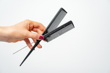 Female hand holding hair comb against white background