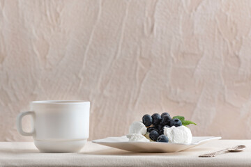 Meringue cake decorated with blueberries next to white cup. Delicious dessert.