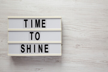 'Time to shine' on a lightbox on a white wooden surface, top view. Flat lay, overhead, from above....