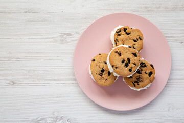 Homemade Chocolate Chip Cookie Ice Cream Sandwich on a pink plate on a white wooden background, top view. Overhead, from above, flat lay. Copy space.