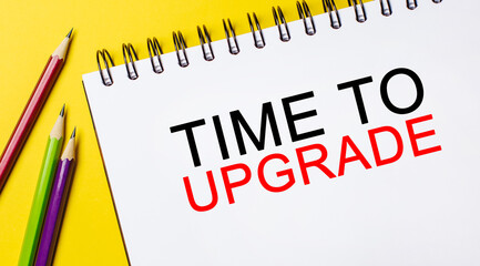 Text Time to upgrade on a white notepad with pencils on a yellow background. Business concept