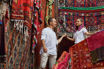 Couple in love chooses a Turkish carpet at the market. Cheerful joyful emotions on the face of a...