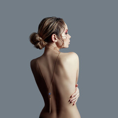 Art of Nude fashion Nude back blonde on grey background, pendant necklace on chain on back. The...