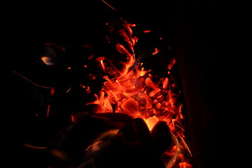 Fototapeta na wymiar Blurry bokeh of burning charcoal in the dark.