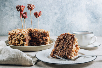 Chocolate cake with caramel cream and peanut on concrete background. Decorated with marshmallow hearts in chocolate