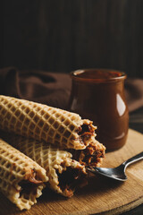 Concept of tasty meal with wafer rolls with condensed milk on wooden background