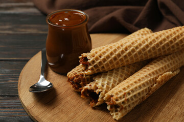 Concept of tasty meal with wafer rolls with condensed milk on wooden background