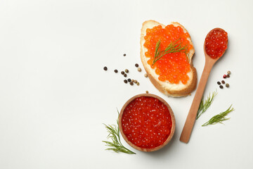 Sandwich, wooden bowl and spoon with caviar on white background, space for text