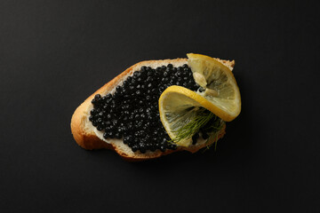Delicious sandwich with caviar on black background