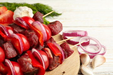Cutting board with shish kebab and ingredients on wooden background