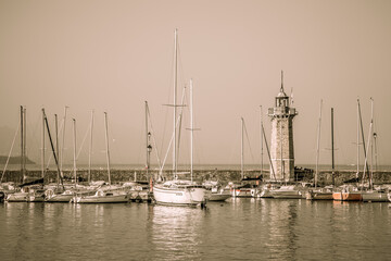A bay with a marina and the ancient lighthouse of Desenzano del Garda. Early autumn evening. Lombardy, Italy