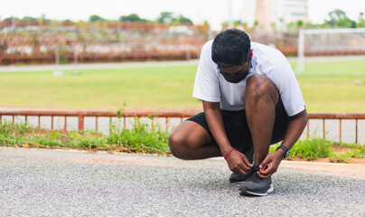 Close up Asian sport runner black man wear watch sitting he trying shoelace running shoes getting...