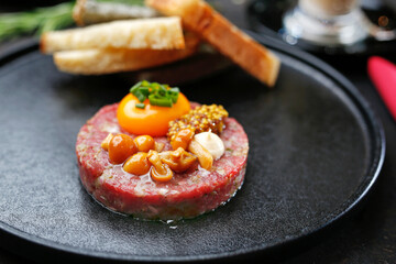 Beef tartare with yolk, pickled mushrooms and mustard. Traditional appetizer.
Serving the dish.