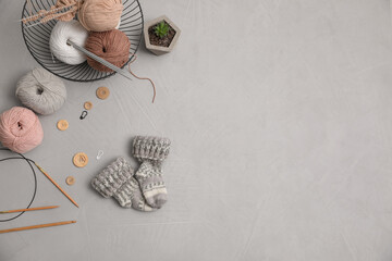 Flat lay composition with threads and knitted mittens on grey background, space for text. Engaging...