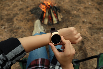 Woman using stylish smart watch outdoors, closeup