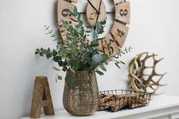 Beautiful eucalyptus branches on mantelpiece in modern room. Interior design