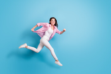 Full length profile photo of pretty carefree person jump run speedy good mood isolated on blue color background