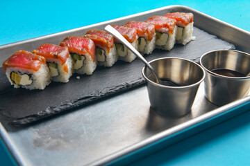 Sushi Set: sashimi and sushi rolls on blue background. Traditional Japanese cuisine concept, close up.