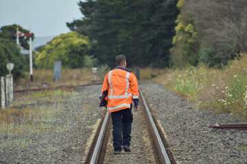 View of railroad worker walking away between rail tracks