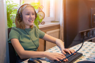 Teenager girl in green clothes with black headphones for remote learning via a computer from home room. Distance learning online education. Gamer. Self-isolation. Quarantine time