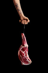 Hand of a butcher holds raw leg of lamb