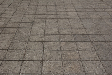 The sidewalk is paved with square decorative tiles.