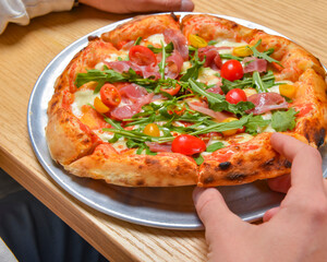 Young man eating a slice of pizza margherita. Still life, eating out concept. At restaurant or at home, pizza delivery.
