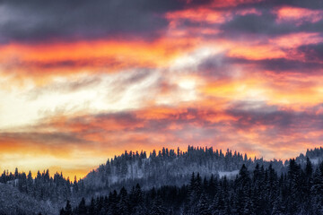 Colorful clouds on evening sky and winter mountains at background