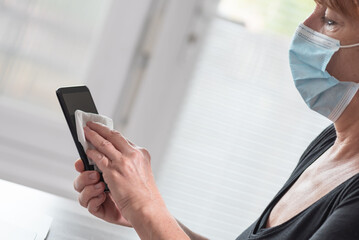 Woman disinfecting smartphone; prevention of virus and bacteria infection