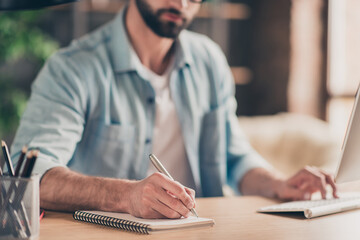 Photo portrait cropped close-up of man taking notes typing on keyboard at desk in modern industrial...