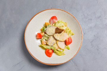 Bowl of Caesar Salad served on a black background in restaurant or diner. Traditional Caesar recipe
