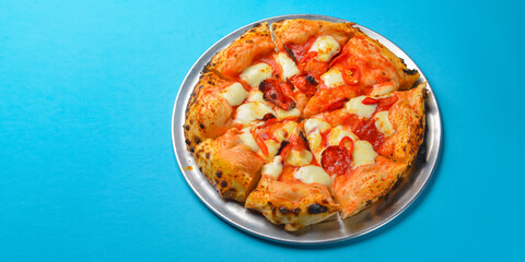 A Pepperoni pizza on a blue background isolated. Traditional Italian cuisine concept, pizza Margarita or Margherita
