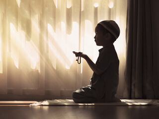 Silhouette image of Muslim pre school kid pray to God (Doing  Dua or supplication).Concept of...