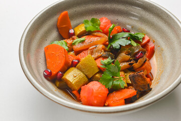 Baked vegetable salad in a cermaic bowl over white background. Delicious healthy autumn or winter salad.