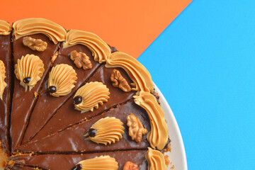 Chocolate cake with icing on top and with nuts over colorful background