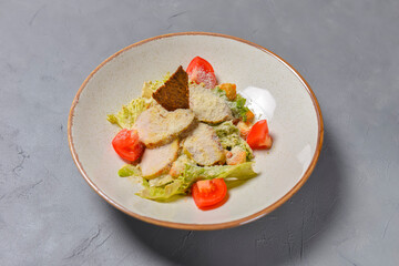 Bowl of Caesar Salad served on a black background in restaurant or diner. Traditional Caesar recipe