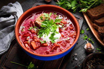 Borscht with sour cream on the wooden table close-up - a dish of traditional Russian and Ukrainian cuisine