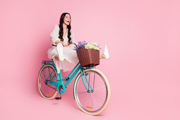 Full length body size photo of crazy female student riding bike with flowers on holidays shouting isolated pastel pink color background